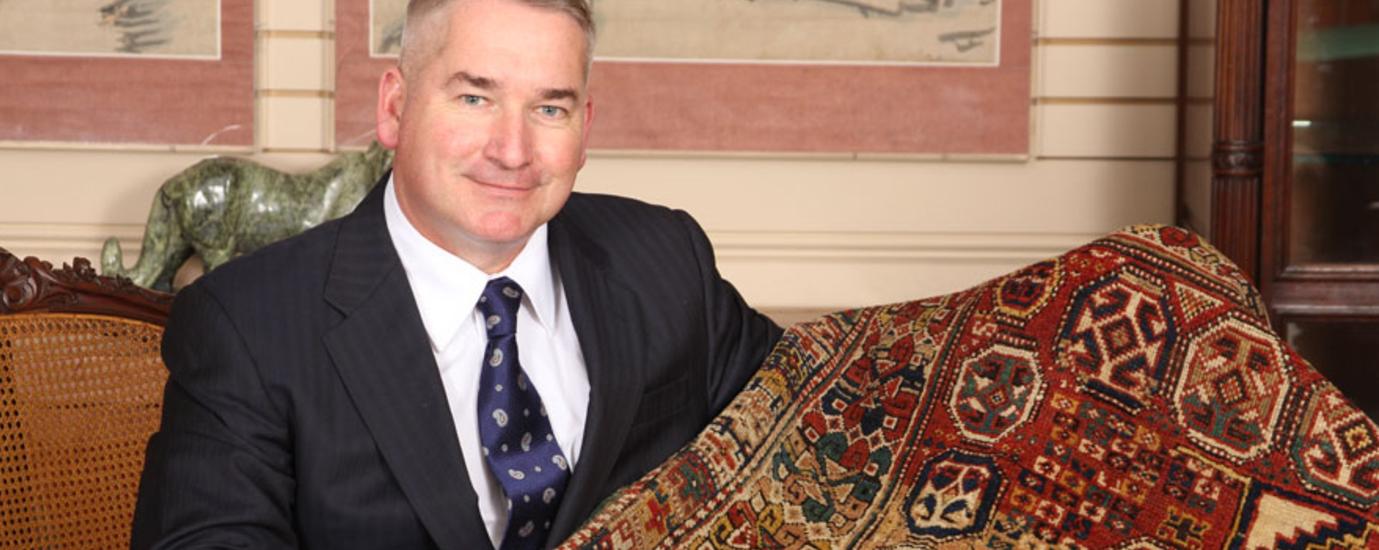 A man in suit and tie holding onto a rug. A man in suit and tie holding onto a rug.