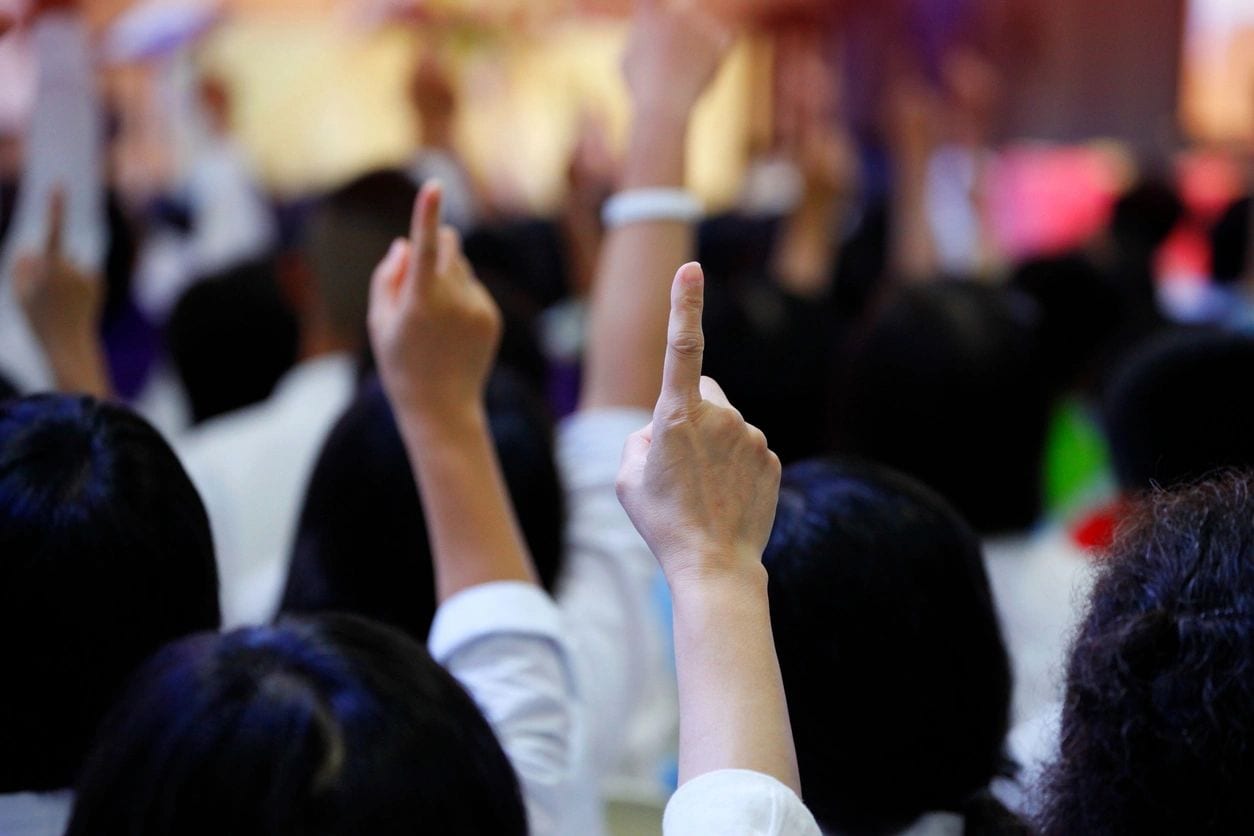 A group of people raising their hands in the air.