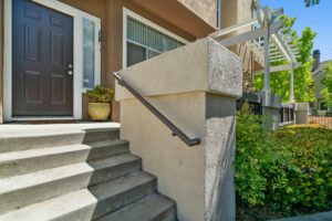 A cement staircase with metal handrail in front of a house.